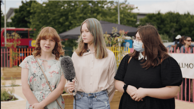 presenter stood in the middle of two other young people, interviewing the person to the left
