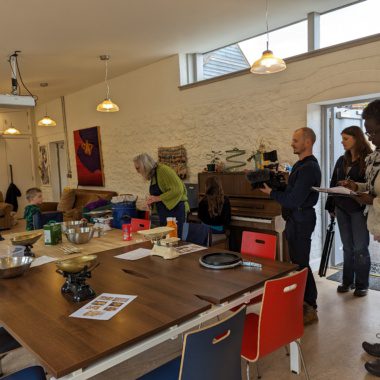 a dinner table at a youth centre, a man is filming the scene
